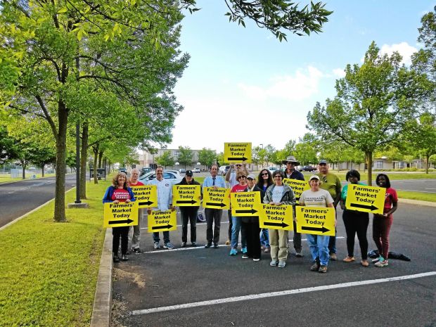 15 people holding yellow signs with the words farmers' market today and an arrow on them