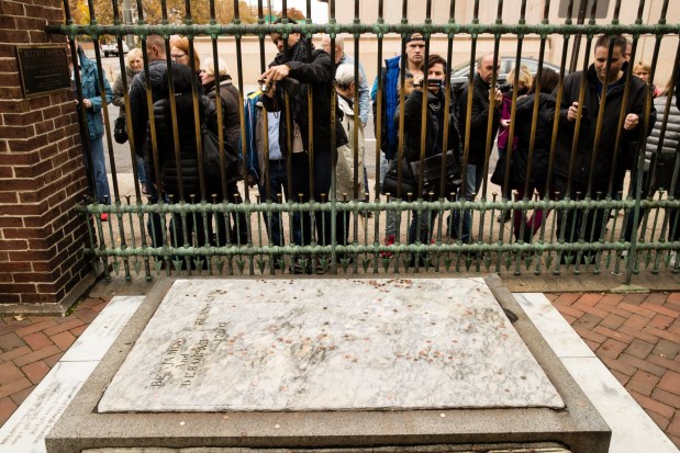 Tourists peer through a fence at Benjamin Franklin's grave at the Christ Church Burial Ground in Philadelphia. (AP Photo/Matt Rourke)