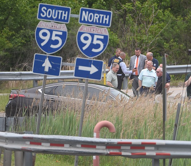 Investigators examine a sedan Tuesday in the 2300 block of Market Street at the Interstate 95 on ramp. (PETE BANNAN-DAILY TIMES)