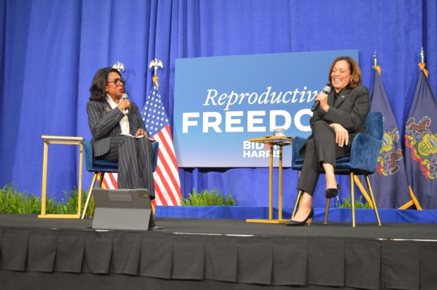 2 women seated on a stage with microphones.