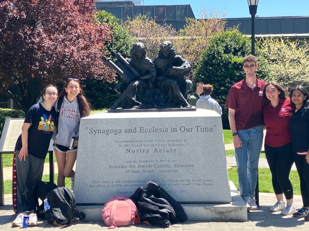 During Spring Fling 2024, SJU students flank the "Synagoga et Ecclesia In Nostra Aetate" commemoration of the 1967 foundation of The Institute for Jewish-Catholic Relations on Hawk Hill. (Photo submitted by Mary Brown)