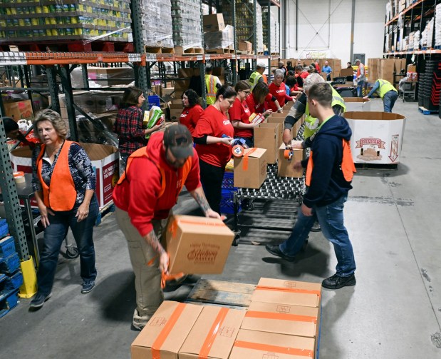 Giant employees and other volunteers pack food boxes Wednesday at Helping Harvest, 117 Morgan Drive, Spring Township. (BILL UHRICH -READING EAGLE)