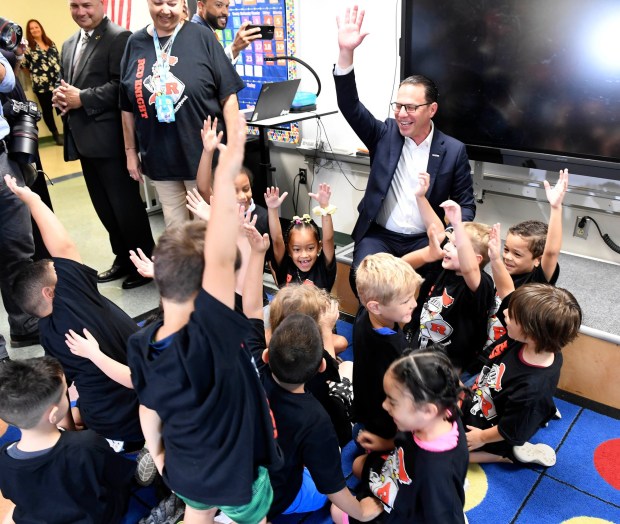 Gov. Josh Shapiro leads a Red Knights cheer in a huddle with kindergarten students during a visit to Millmont Elementary School Friday. (BILL UHRICH - READING EAGLE)